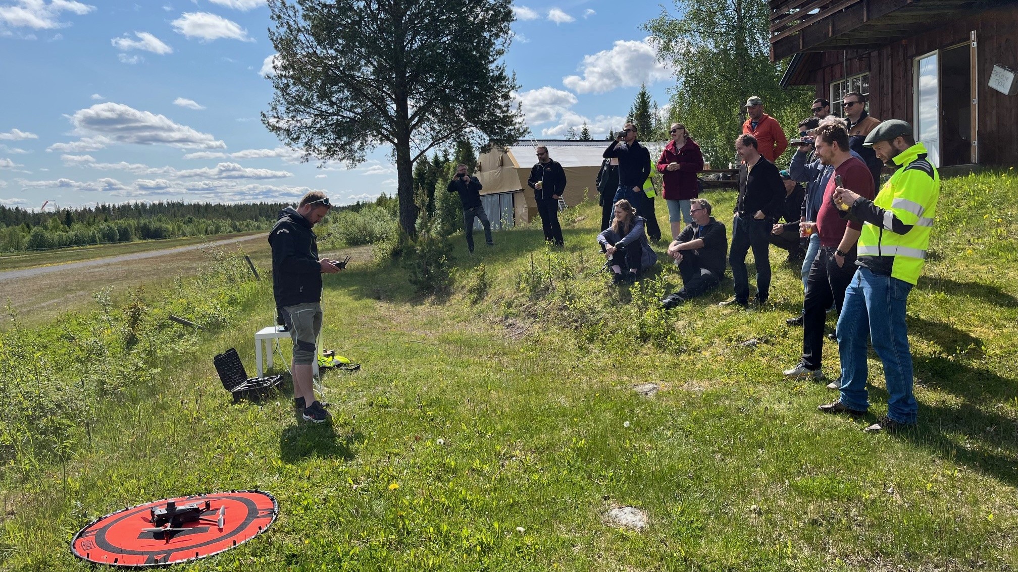 Flere personer st&aring;r og ser p&aring; en mann som ska fly drone